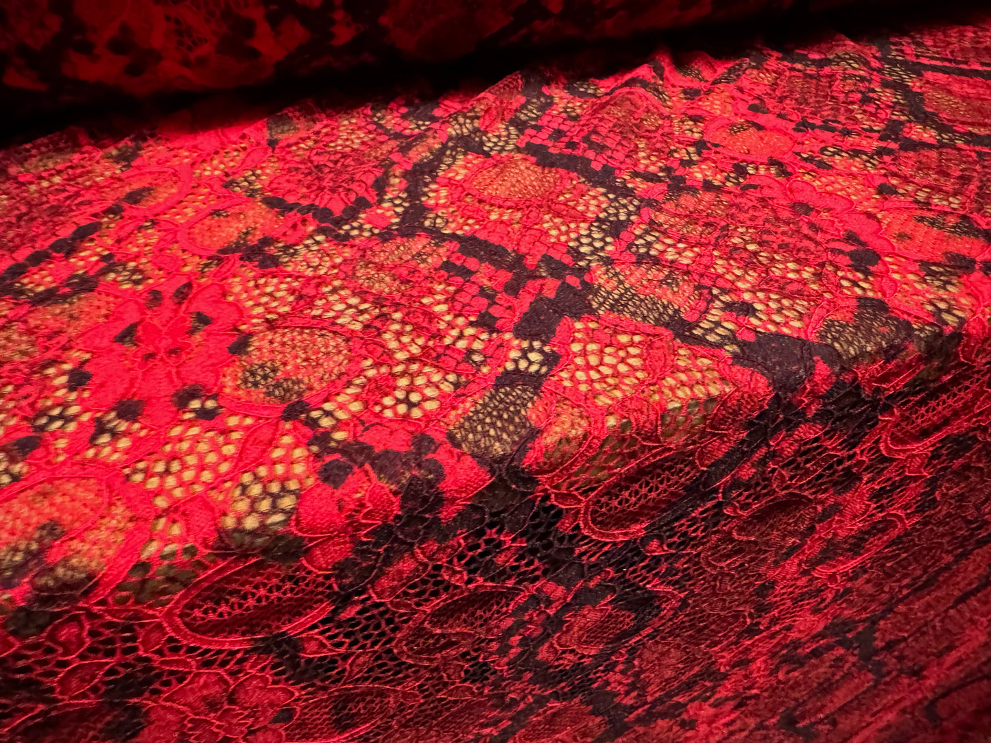 Stretch lace dress fabric with scalloped selvedge, per metre - snakeskin animal print - red & black